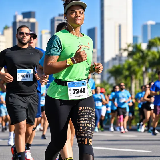 Patrícia de camiseta verde e número de peito do Circuito RJ 5K, com prédios ao fundo