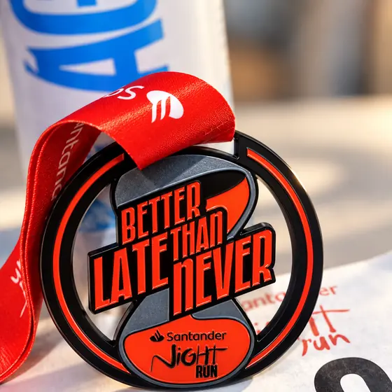 Medalha Better Late Than Never da Santander Night Run, preta e laranja