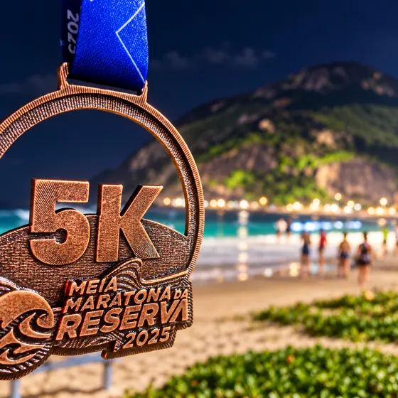 Medalha de bronze 5K da Meia Maratona da Reserva 2025 com a praia ao fundo