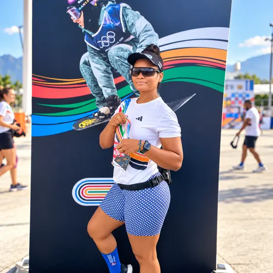 Patrícia de óculos escuros e boné posando com a medalha da Corrida Time Brasil